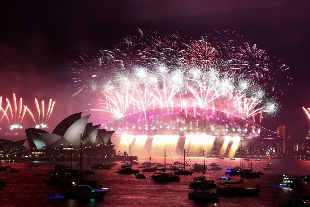  New Year's Eve fireworks erupt over Sydney's iconic Harbour Bridge and Opera House (L) during the fireworks show on January 1, 2022. (Photo by DAVID GRAY / AFP)
      