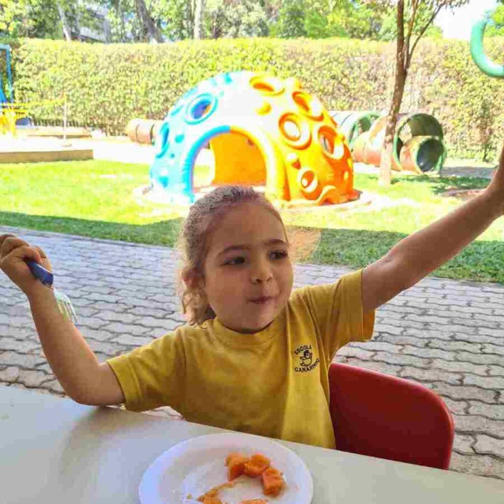 Aluna da Escola Canarinho comendo mamão no lanche da escola