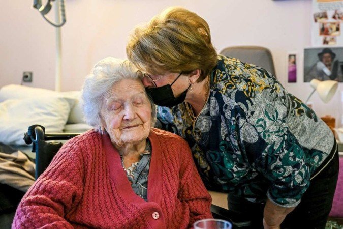  Aline Blain, 110 anos, é beijada por sua filha Monique em seu quarto na casa de repouso em 31 de janeiro de 2022 em Valreas, no sul da França. (Foto de Nicolas Tucat/AFP)
      