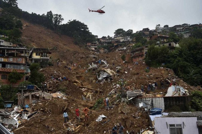  A helicopter of a fire services rescue team overflies an area of a mudslide looking for survivors in Petropolis, Brazil on February 16, 2022.  Large scale flooding destroyed hundreds of properties and claimed at least 34 lives in the area.  (Photo by CARL DE SOUZA / AFP)
      Caption 