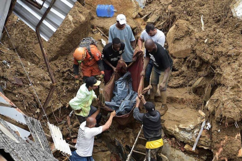 Conteúdo Gráfico: Pessoas carregam o cadáver de uma vítima dos escombros após um deslizamento de terra em Petrópolis, Brasil, em 16 de fevereiro de 2022