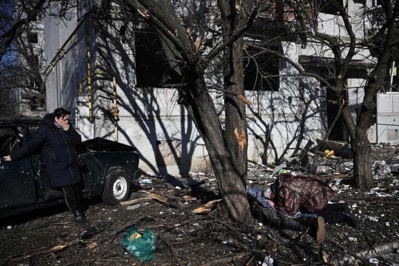  People react beside the body of a relative outside a destroyed building after bombings on the eastern Ukraine town of Chuguiv on February 24, 2022, as Russian armed forces are trying to invade Ukraine from several directions, using rocket systems and helicopters to attack Ukrainian position in the south, the border guard service said. Russias
      