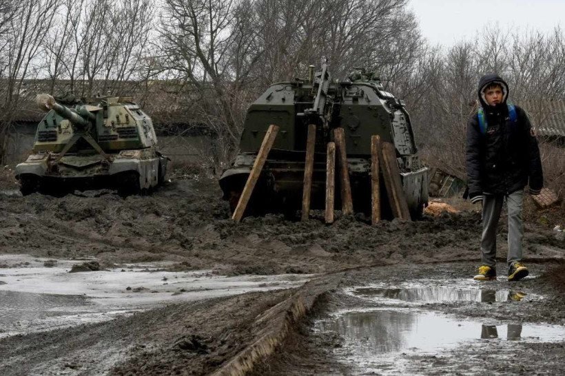  A boy walks in front of Russian armored vehicles parked at a railway station in the southern Russian Rostov region on February 25, 2022. (Photo by STRINGER / AFP)
      