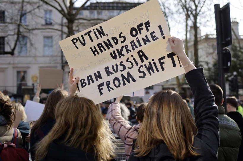 Manifestantes seguram um cartaz pedindo que a Rússia seja banida do sistema bancário Swift enquanto participam de uma manifestação de protesto do lado de fora da Embaixada da Rússia em Londres, em 26 de fevereiro de 2022, após a invasão da Ucrânia pela Rússia. - O governo do Reino Unido ordenou na sexta-feira que todos os bens do presidente Vladimir Putin e seu ministro das Relações Exteriores Sergei Lavrov fossem congelados devido à invasão da Ucrânia pela Rússia.      