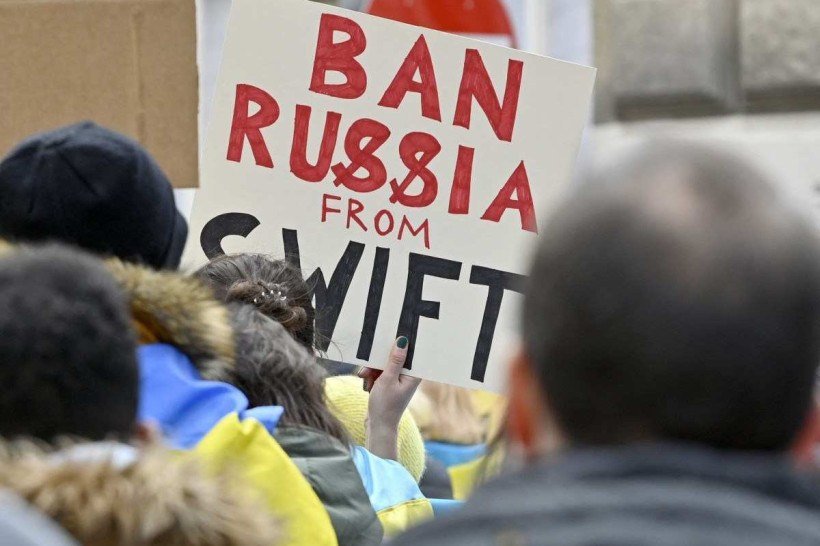  A demonstrator holds a poster reading 'Ban Russia from SWIFT' during a protest against Russia's invasion of Ukraine, on February 26, 2022 in front of the Russian embassy in Vienna, Austria. (Photo by HANS PUNZ / APA / AFP) / Austria OUT
      Caption 