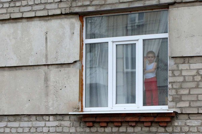 Criança acena na janela de um prédio em Lugansk, uma das regiões mais afetadas pela guerra -  (crédito: Anatolii Stepanov/AFP)