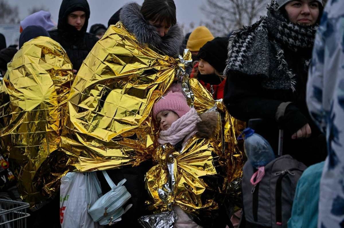  People wait in freezing cold temperatures to be transferred to a train station, after crossing the Ukrainian borders into Poland, at the Medyka border crossing in Poland, on March 7, 2022. More than 1,5 million people have fled Ukraine since the start of the Russian invasion, according to the latest UN data on March 6, 2022.  (Photo by Louisa GOULIAMAKI / AFP)
      