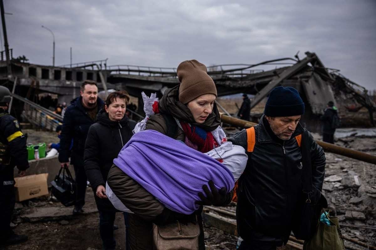  A woman carrying her baby crosses a destroyed bridge as they flee the city of Irpin, northwest of Kyiv, on March 7, 2022. Ukraine dismissed Moscow's offer to set up humanitarian corridors from several bombarded cities on Monday after it emerged some routes would lead refugees into Russia or Belarus. The Russian proposal of safe passage from Kharkiv, Kyiv, Mariupol and Sumy had come after terrified Ukrainian civilians came under fire in previous ceasefire attempts. (Photo by Dimitar DILKOFF / AFP)

      