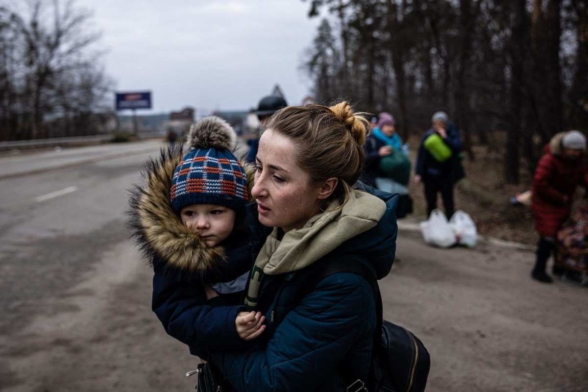  A woman carries her child as they flee the city of Irpin, northwest of Kyiv, on March 7, 2022. Ukraine dismissed Moscow's offer to set up humanitarian corridors from several bombarded cities on Monday after it emerged some routes would lead refugees into Russia or Belarus. The Russian proposal of safe passage from Kharkiv, Kyiv, Mariupol and Sumy had come after terrified Ukrainian civilians came under fire in previous ceasefire attempts. (Photo by Dimitar DILKOFF / AFP)

      