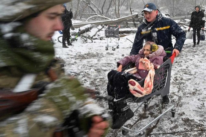 A man pushes a cart with an elderly woman while evacuating civilians from the city of Irfin.  Northwest of Kiev: More than 2 million refugees