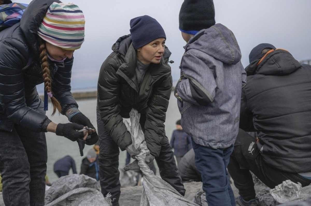  A woman from Odessa talks to her son as they fill bags with sand for frontlines, along the beach of the Black Sea city of Odessa, in the southern Ukraine on March 7, 2022. - Odessa, which Ukraine fears could be the next target of Russia's offensive in the south, is the country's main port and is vital for its economy. But the city of one million people close to the Romanian and Moldovan borders also holds a special place in the Russian imagination. (Photo by BULENT KILIC / AFP)
      