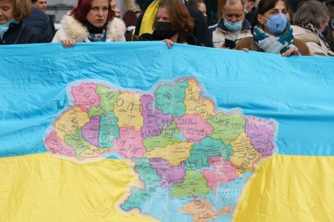 Manifestantes com bandeira que tem o mapa com território da Ucrânia, alvo de disputas no conflito - (crédito: Getty Images) Manifestantes com bandeira que tem o mapa com território da Ucrânia, alvo de disputas no conflito - (crédito: Getty Images)