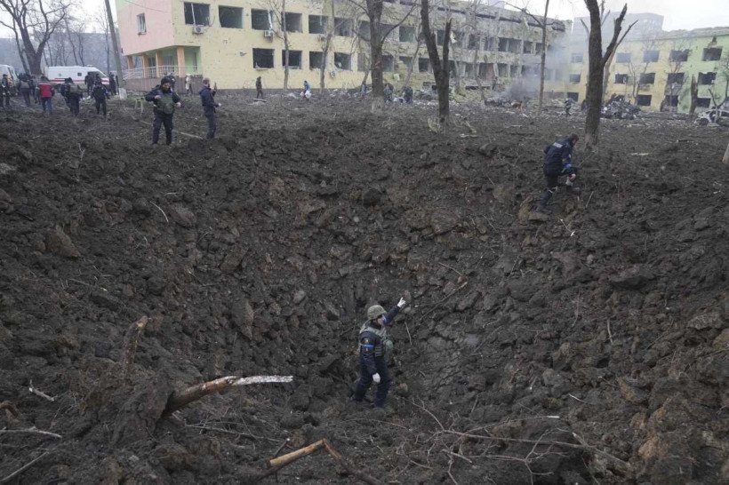 A man carries his child away from the damaged by shelling maternity hospital in Mariupol, Ukraine, Wednesday, March 9, 2022. A Russian attack has severely damaged a maternity hospital in the besieged port city of Mariupol, Ukrainian officials say. (AP Photo/Evgeniy Maloletka)