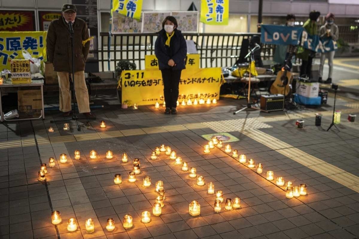  People take part in a candle vigil in memory of earthquake and tsunami victims in Mitaka, on the outskirts of Tokyo on March 11, 2022, on the 11th anniversary of the 9.0 magnitude earthquake which triggered a tsunami and nuclear disaster. (Photo by CHARLY TRIBALLEAU / AFP)
      