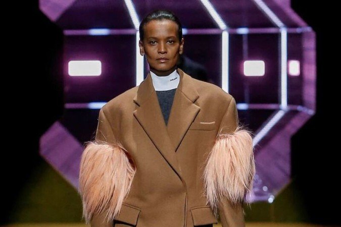O desfile feminino de Outono-Inverno 2022 da Prada, exibido na Milão Fashion Week, foi marcado por uma alfaiataria dinâmica, ombros com silhueta trapézio e bem estruturados. Alguns modelos, como esse casaco, vieram com plumas.