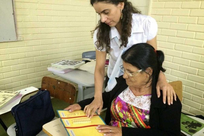 Aluna sendo auxiliada pela alfabetizadora Regina Celi no Centro Educacional 11, no P Norte, em 2015