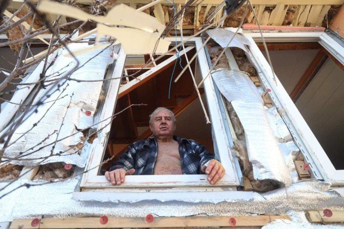 Morador olha pela janela de sua casa destruída, em Odessa 