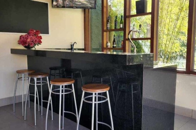  2022. Revista. Casa. Bar em casa feito com bancada de mármore e espaço amplo.        