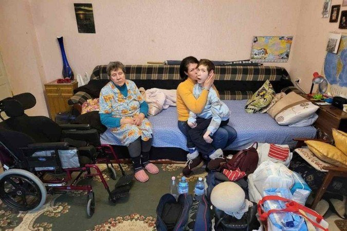 Após serem resgatados, a ex-sogra, ex-mulher e o filho com paralisia cerebral estão em um abrigo em Dnipro, cidades sem bombardeios e com oferta de comida - (crédito: News Boletim/Reprodução) Após serem resgatados, a ex-sogra, ex-mulher e o filho com paralisia cerebral estão em um abrigo em Dnipro, cidades sem bombardeios e com oferta de comida - (crédito: News Boletim/Reprodução)