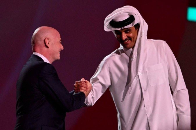  O Presidente da FIFA Gianni Infantino (L) aperta a mão do Emir Sheikh Tamim bin Hamad al-Thani (R) do Qatar no palco durante o sorteio da Copa do Mundo de 2022 no Qatar, no Centro de Exposições e Convenções de Doha, em 1º de abril de 2022. (Foto de François-Xavier MARIT / AFP)      