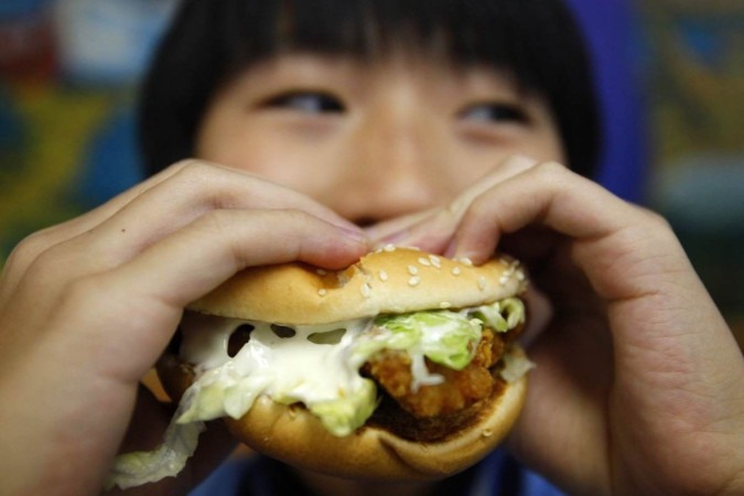  A boy poses with a chicken burger at a fast food outlet in Taipei January 29, 2010. The Taiwan Department of Health on Thursday proposed a ban on junk food advertisements aired around children's television programmes, to tackle the growing child obesity rate, said officials.    REUTERS/Nicky Loh (TAIWAN - Tags: SOCIETY FOOD HEALTH MEDIA)
      Caption 