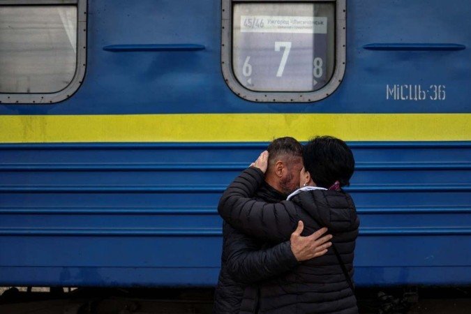 Homem abraça esposa em estação ferrovária de Donbass