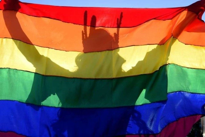 As vagas destinadas ao público representado pela bandeira arco-íris registraram aumento de 2% em dois anos The shadow of a reveler is cast on a rainbow flag during the 22nd LGBT Pride Parade, which theme is "50 years of Stonewall", in Brasilia, on July 14, 2019. / AFP / EVARISTO SA Caption