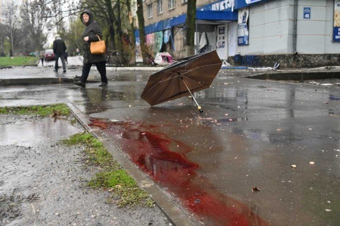 Mulher caminha perto de local bombardeado pelas forças russas, em Kharkiv, a segunda maior cidade da Ucrânia