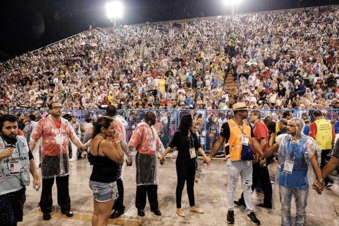 Pessoas fazem um cordão de isolamento enquanto bombeiros atendem pessoas atropeladas por um carro alegórico da escola de samba Paraíso do Tuiuti em 2017 -  (crédito: AFP / Yasuyoshi CHIBA)