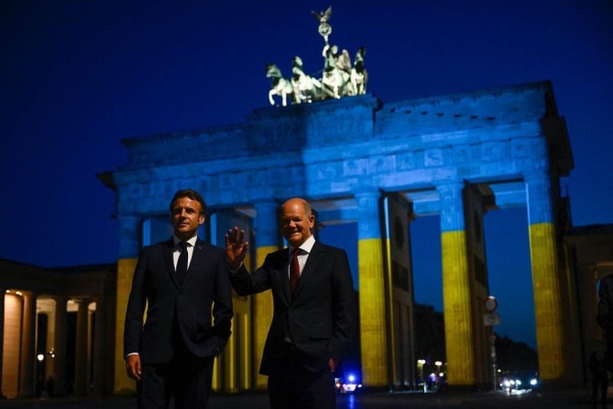 Olaf Scholz (R) and Emmanuel Macron (L) visit the Brandenburg Gate illuminated in Ukrainian colors