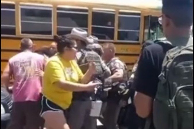 Policiais contêm moradores, enquanto mulher se desespera, diante do centro de ensino