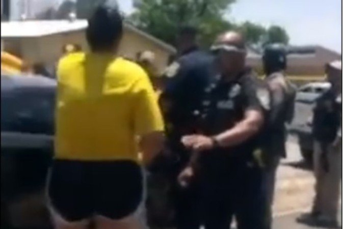 Pouco depois, um agente (D) gesticula para a mesma mulher, a fim de evitar que ela fure o bloqueio de segurança e entre no prédio