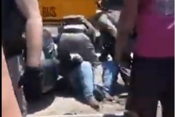 Oficial imobiliza mãe de estudante, jogada ao chão, entre dois carros: truculência registrada em vídeo foi criticada nas redes sociais