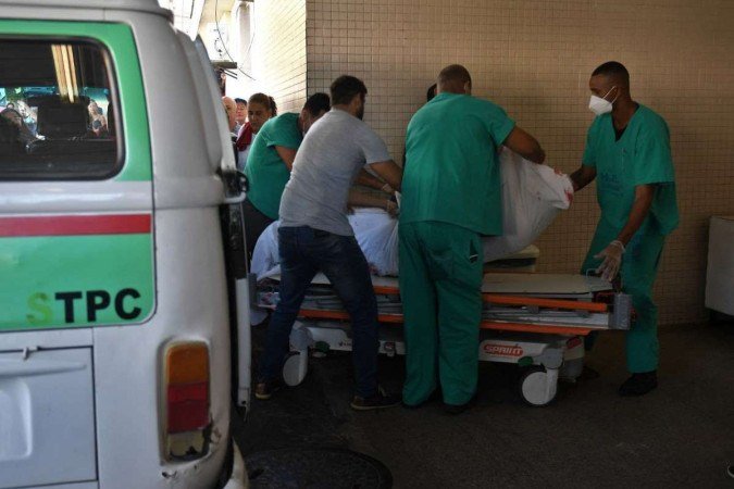 O cad&aacute;ver de uma v&iacute;tima &eacute; carregado em uma maca no Hospital Getulio Vargas -  (crédito: MAURO PIMENTEL / AFP)