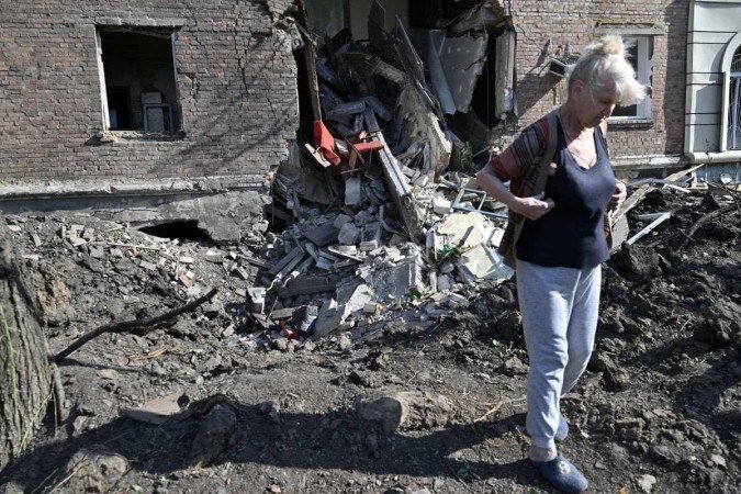 Mulher caminha em frente a prédio residencial atingido em Bakhmut
