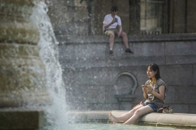 Jovem se refresca em fonte da Trafalgar Square, em Londres