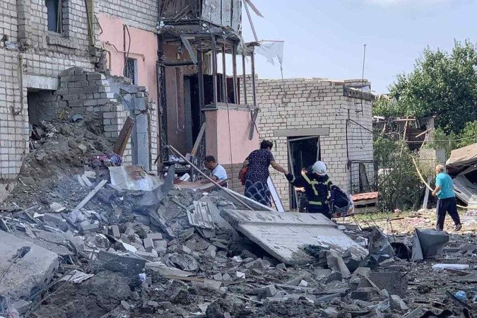 Bombeiros e civis caminham entre os escombros após o ataque russo em Voznesenk, no sul da Ucrânia - (crédito: AFP) Bombeiros e civis caminham entre os escombros após o ataque russo em Voznesenk, no sul da Ucrânia - (crédito: AFP)