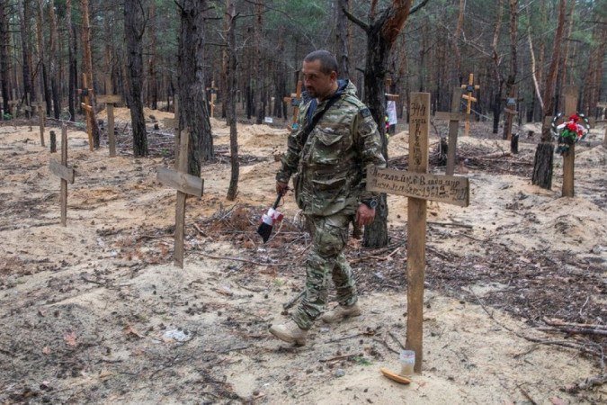 Um soldado caminha entre os túmulos encontrados na floresta - (crédito: Reuters) Um soldado caminha entre os túmulos encontrados na floresta - (crédito: Reuters)