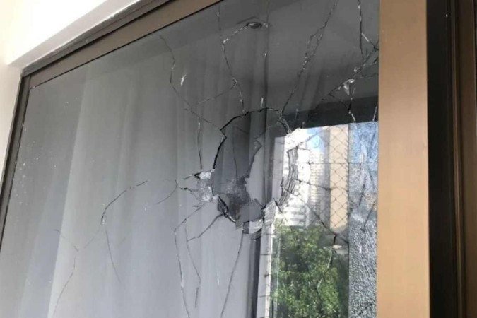 Segundo informações do portal g1, balas destruíram os vidros da varanda do apartamento - (crédito: Reprodução/Redes sociais/WhatsApp) Segundo informações do portal g1, balas destruíram os vidros da varanda do apartamento - (crédito: Reprodução/Redes sociais/WhatsApp)