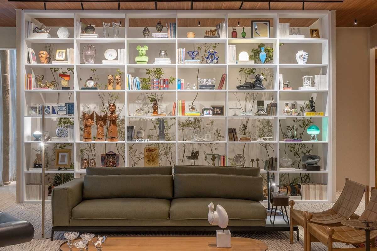 Estante repleta de obras de arte e memorabilia no Particu-Lar E Infinito, de Helio Albuquerque