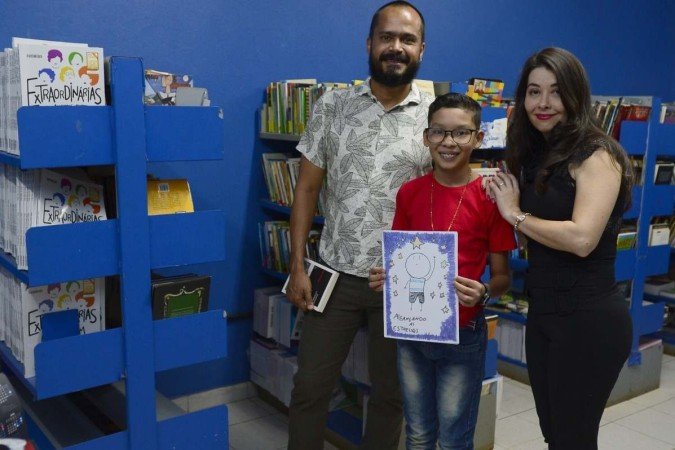 Diogo Pietro, com o vice-diretor Josuel Santos e a professora Marcia Videira. A escola auxilia o aluno no processo de publicação do primeiro livro, Alcançando as Estrelas. 