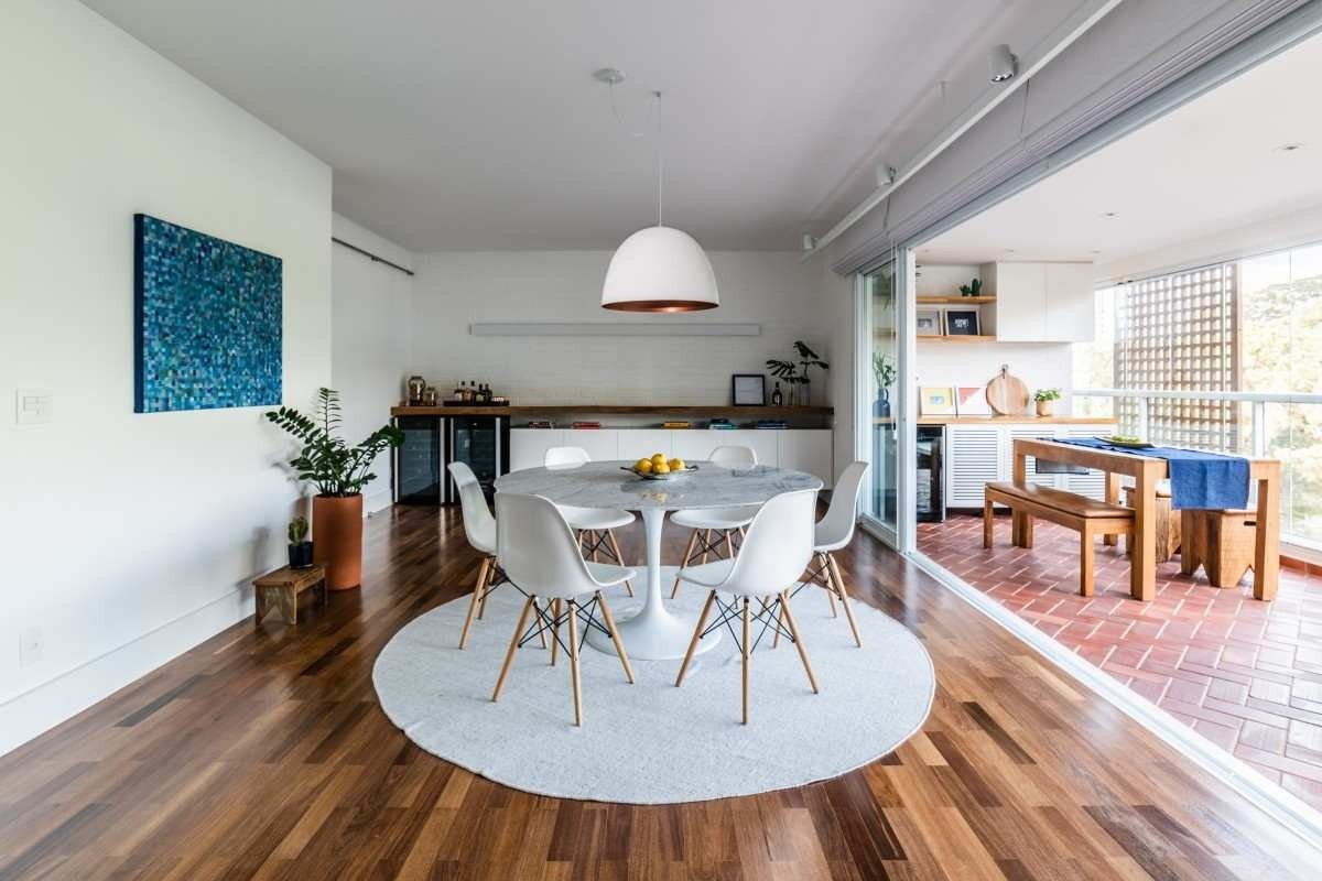 A cor branca segue uníssona com o pendente central, a mesa redonda, as cadeiras e o tapete que delimita o ambiente assinado pela arquiteta Júlia Guadix 