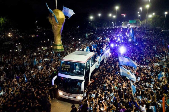 This aerial image taken on December 20, 2022 shows Argentinas players celebrating on board a bus with supporters after winning the Qatar 2022 World Cup tournament as they leave Ezeiza International Airport en route to the Argentine Football Association (AFA) training centre in Ezeiza, Buenos Aires province, Argentina. (Photo by Tomas CUESTA / AFP) - (crédito: Tomas CUESTA / AFP) This aerial image taken on December 20, 2022 shows Argentinas players celebrating on board a bus with supporters after winning the Qatar 2022 World Cup tournament as they leave Ezeiza International Airport en route to the Argentine Football Association (AFA) training centre in Ezeiza, Buenos Aires province, Argentina. (Photo by Tomas CUESTA / AFP) - (crédito: Tomas CUESTA / AFP)