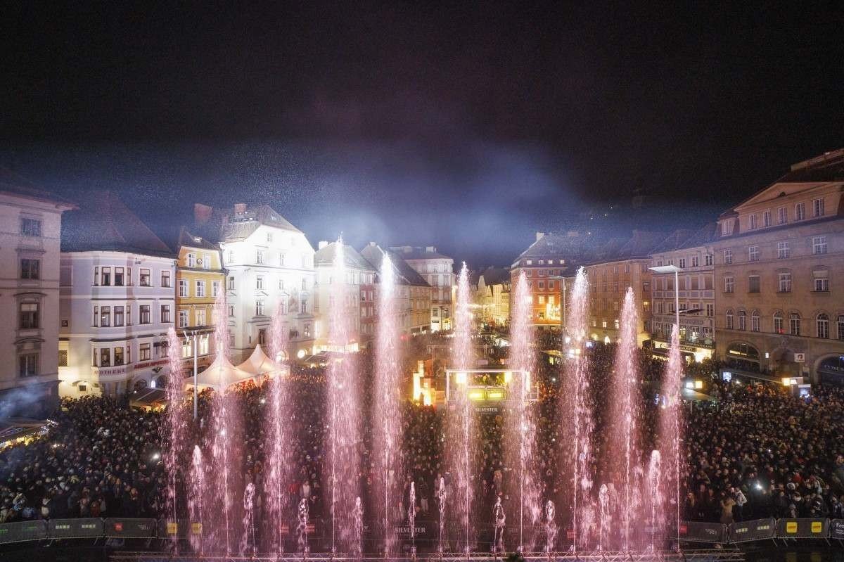Centenas de turistas e cidadãos assistem a um show de água e laser para comemorar o Ano Novo 2023 na praça principal de Graz, na Áustria 