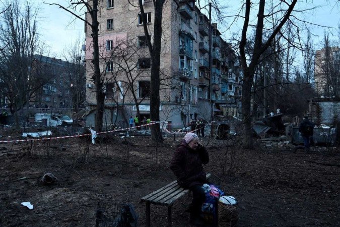 Uma moradora fala ao telefone perto de uma cratera deixada por um ataque russo em frente a um prédio residencial na capital ucraniana Kyiv em 31 de dezembro de 2022. Ataques russos atingiram a Ucrânia, incluindo a capital Kyiv, poucas horas antes das comemorações de Ano Novo enquanto russo - (crédito: SERGEI CHUZAVKOV / AFP) Uma moradora fala ao telefone perto de uma cratera deixada por um ataque russo em frente a um prédio residencial na capital ucraniana Kyiv em 31 de dezembro de 2022. Ataques russos atingiram a Ucrânia, incluindo a capital Kyiv, poucas horas antes das comemorações de Ano Novo enquanto russo - (crédito: SERGEI CHUZAVKOV / AFP)