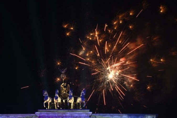 Fogos de artifício explodem sobre o marco histórico de Berlim, o Portão de Brandemburgo, durante um show de luz e música de Ano Novo antes da meia-noite para dar as boas-vindas ao ano de 2023, em 1º de janeiro de 2023. Os oito bilhões de pessoas do mundo começaram a inaugurar 2023 e se despedir de 12 meses turbulentos marcados por guerra na Europa, fortes aumentos de preços, a glória de Lionel Messi na Copa do Mundo e as mortes da rainha Elizabeth, Pelé e do ex-papa Bento XVI.