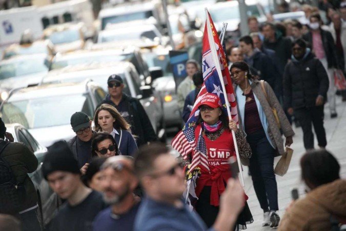 Mulher com camisa, boné e bandeira alusivos ao ex-inquilino da Casa Branca, diante do prédio da Corte 
