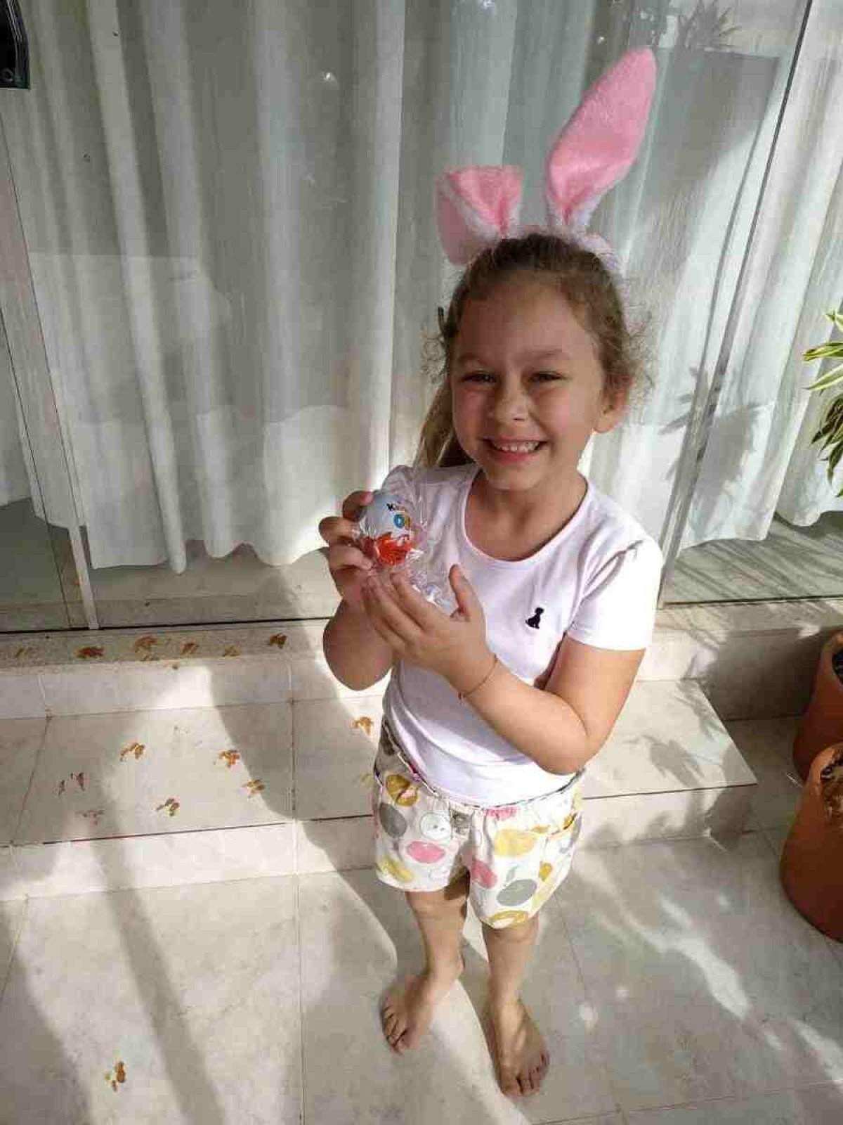 Luiza super sorridente após encontrar uma das surpresas que o coelho arteiro, com as patas sujas de lama, deixou para ela