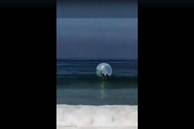 O casal foi empurrado para o mar por falta de controle da bolha e logo gritaram pelos salva-vidas - (crédito: Reprodução/Redes Sociais) O casal foi empurrado para o mar por falta de controle da bolha e logo gritaram pelos salva-vidas - (crédito: Reprodução/Redes Sociais)