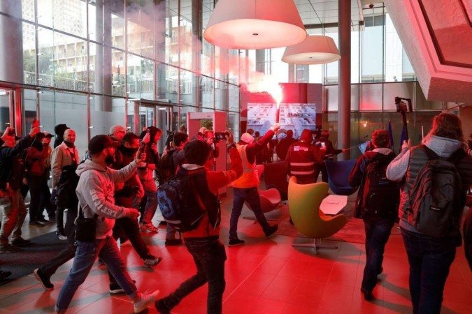Unionists and protesters light flares during a protest action at the headquarters of the Pan-European stock exchange Euronext, a month after the government pushed an unpopular pensions reform act through parliament, in La Defense district, near Paris, on April 20, 2023. - Opposition parties and trade unions have urged protesters to maintain their three-month campaign against the law that will hike the retirement age to 64 from 62. - (crédito: Geoffroy Van der Hasselt / AFP) Unionists and protesters light flares during a protest action at the headquarters of the Pan-European stock exchange Euronext, a month after the government pushed an unpopular pensions reform act through parliament, in La Defense district, near Paris, on April 20, 2023. - Opposition parties and trade unions have urged protesters to maintain their three-month campaign against the law that will hike the retirement age to 64 from 62. - (crédito: Geoffroy Van der Hasselt / AFP)